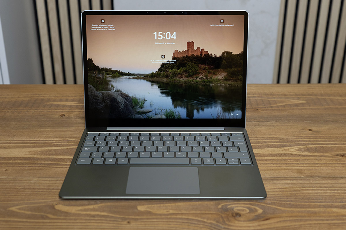 Das Micrsoft Surface Laptop Go 3 liehgt aufgeklappt auf einem Holztisch.