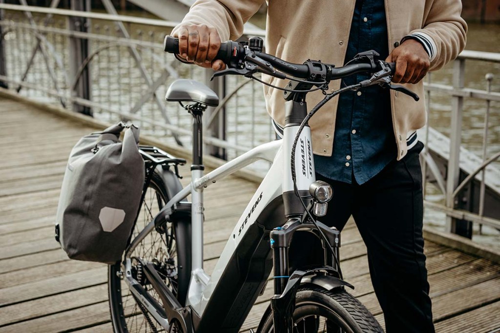 Person im Anschnitt, schiebt ein E-Bike über eine Brücke