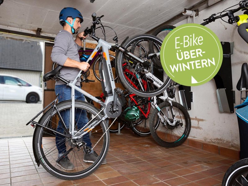 Mann stellt E-Bike in Garage ab.