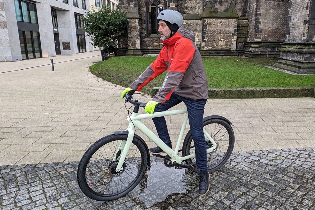 Mann auf E-Bike mit Regenjacke.