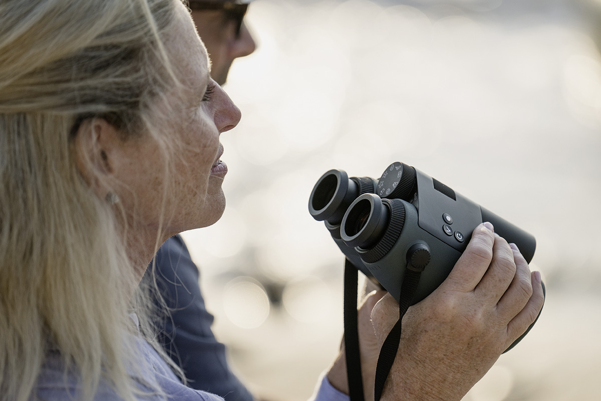 Das Fernglas AX Vision von Swarovski, von einer blonden Frau gehalten.