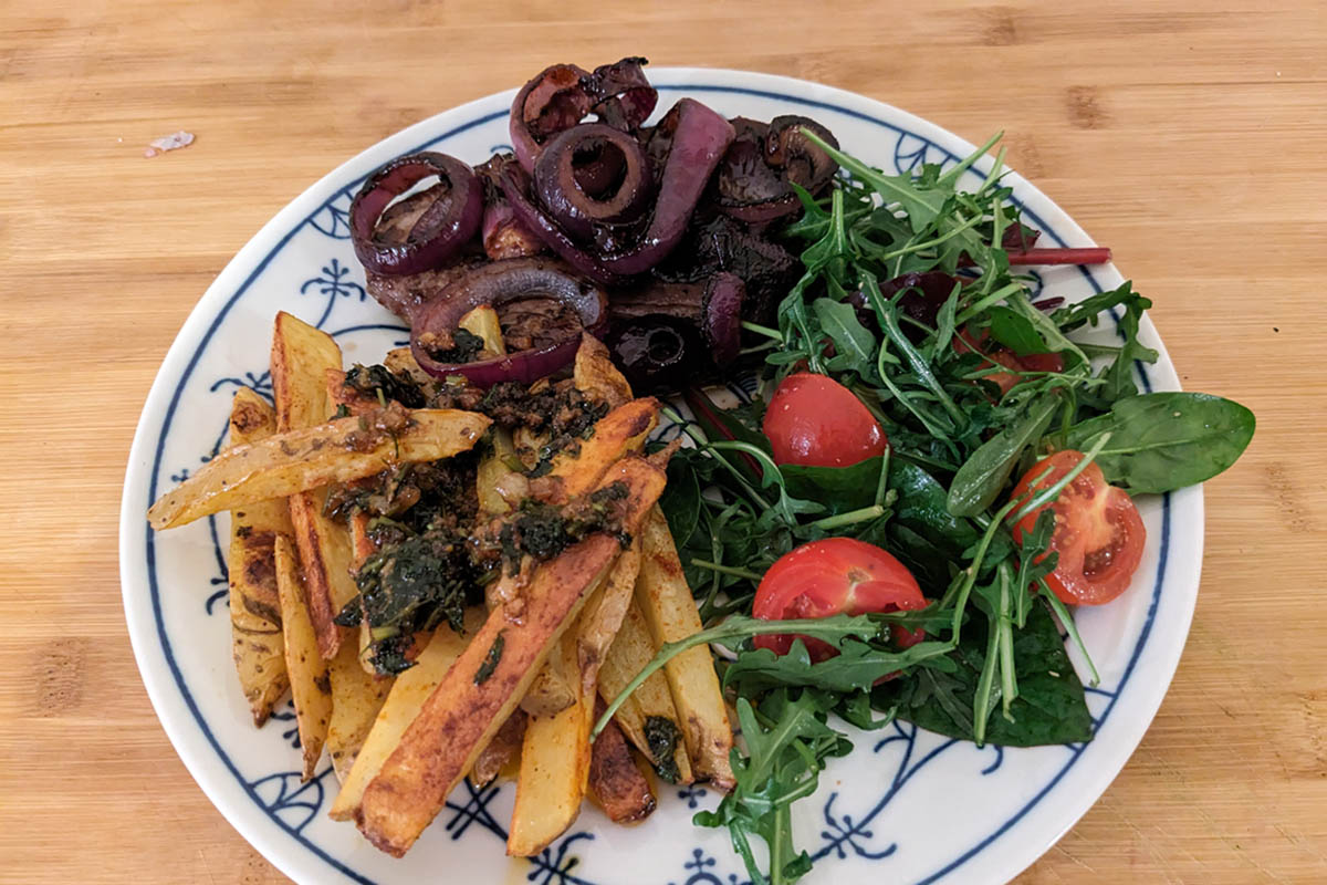 Ein Gericht aus Pommes, Fleisch und Salat auf einem Teller