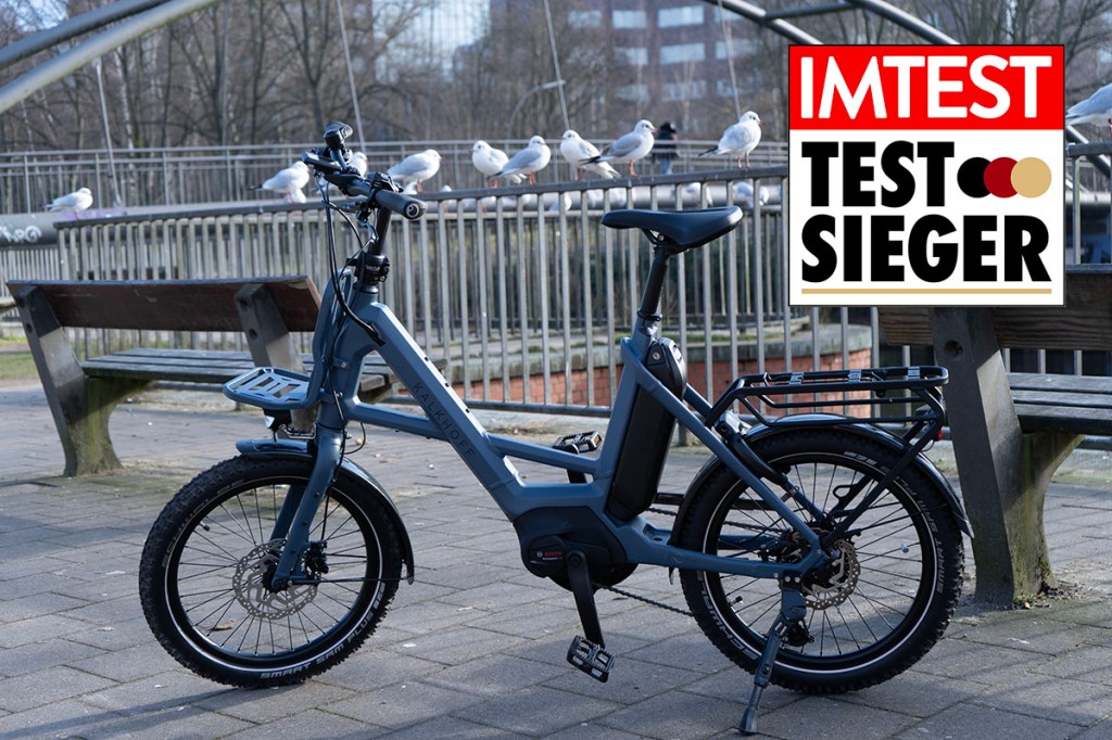 Hellblaues Kompaqkt-E-Bike von Kalkhoff im Profil vor Brückengeländer auf dem Möven sitzen,