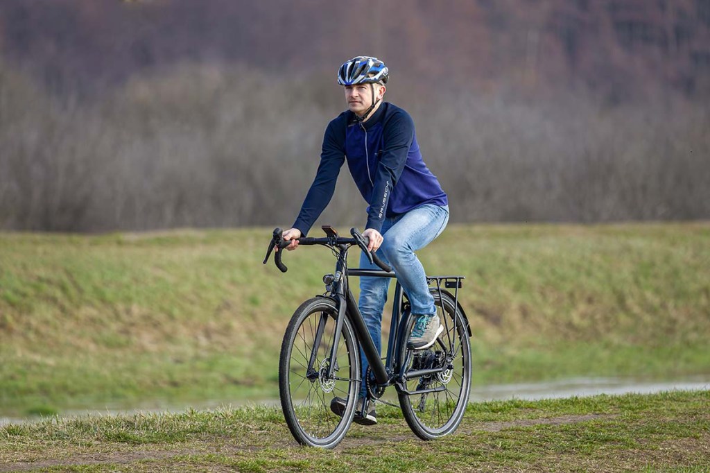 Mann fährt mit einem E-Bike einen Feldweg entlang