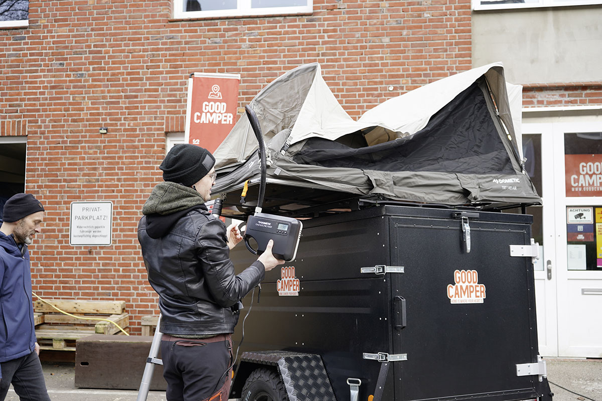 Das auf einem Anhänger montierte Dachzelt Dometic TRT 140 Air wird mit Luft befüllt.