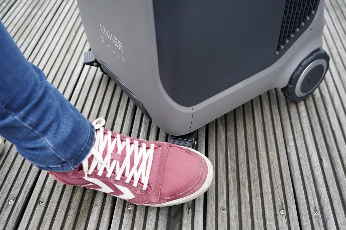 Ein Fuß mit rotem Schuh tritt die Feststell-Bremse an der Anker-Powerstation herunter.