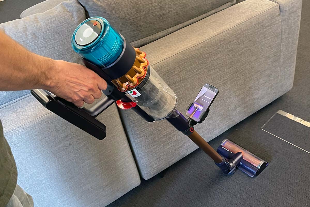 Eine Person saugt mit dem Dyson Gen5detect mit angebautem Smartphone, auf dem CleanTrace läuft.