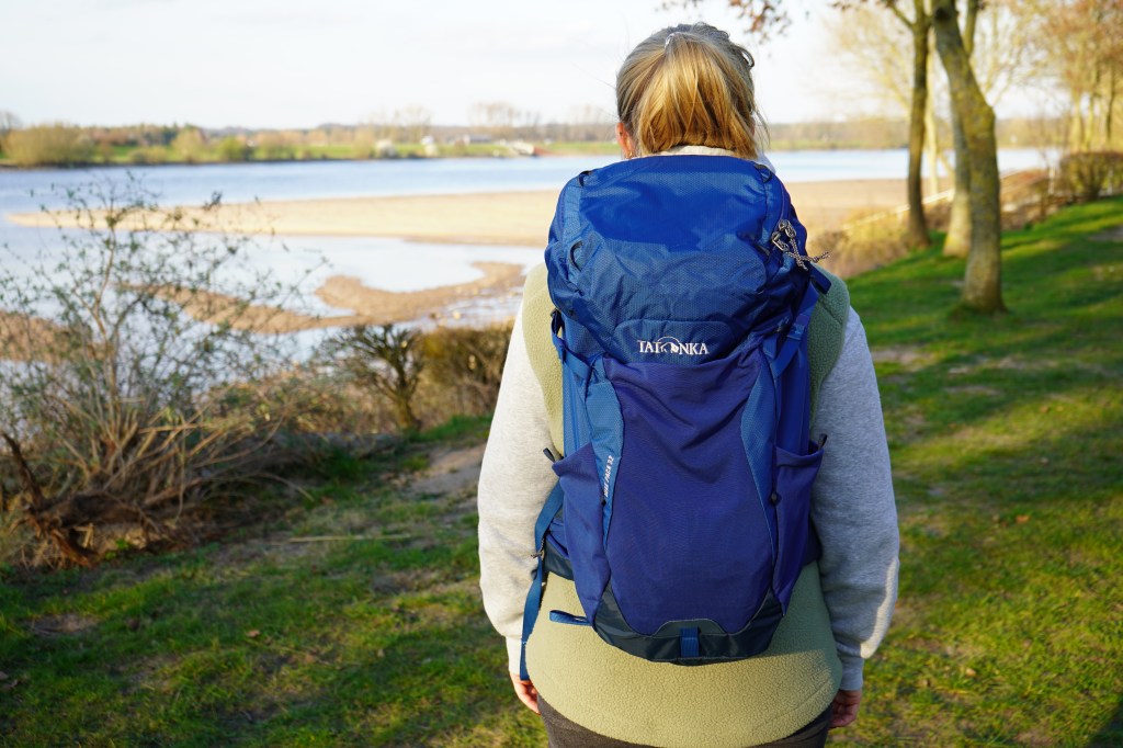 Frau von hinten mit einem blauen Rucksack auf dem Rücken