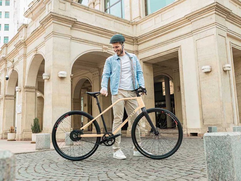 Mann steht vor einem Bambus-E-Bike, altes Gebäude im Hintergrund