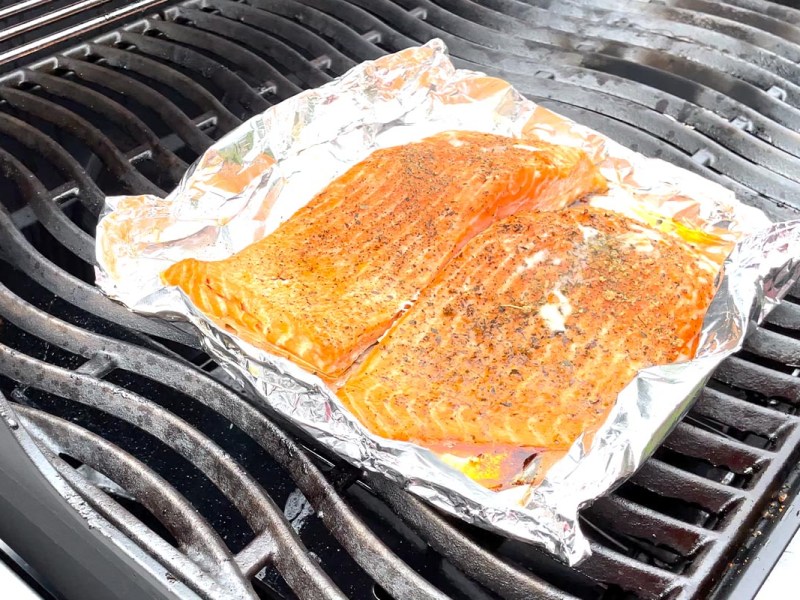 Lachs in Alufolie auf einem Gasgrill.