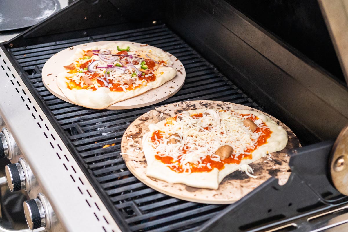 Zwei Pizzen auf einem Gasgrill.