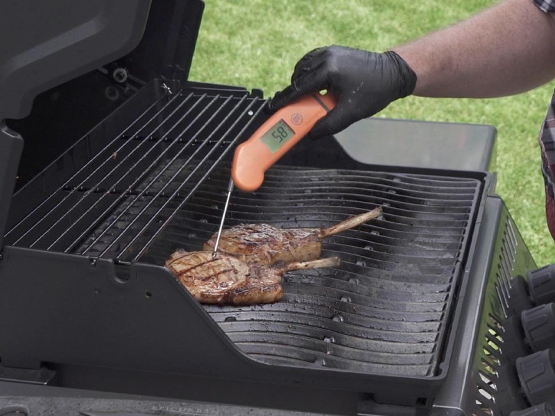 Zwei Stück Fleisch deren Temperatur gemessen wird auf einem Gasgrill.