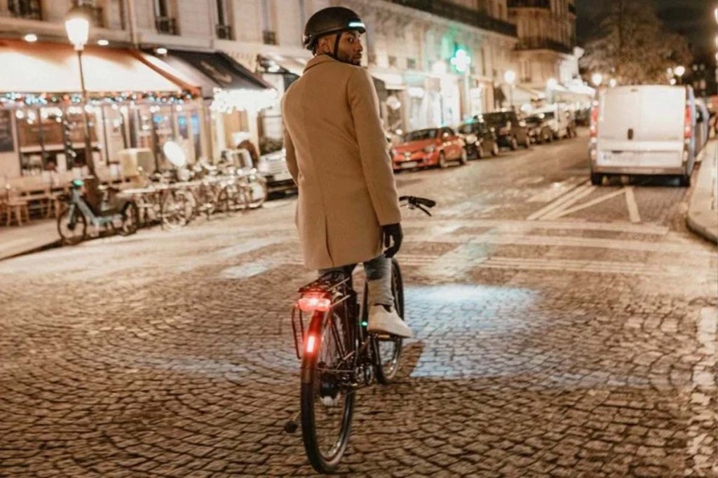 Fahrradfahrer von hinten, der durch eine nächtliche Stadt fährt