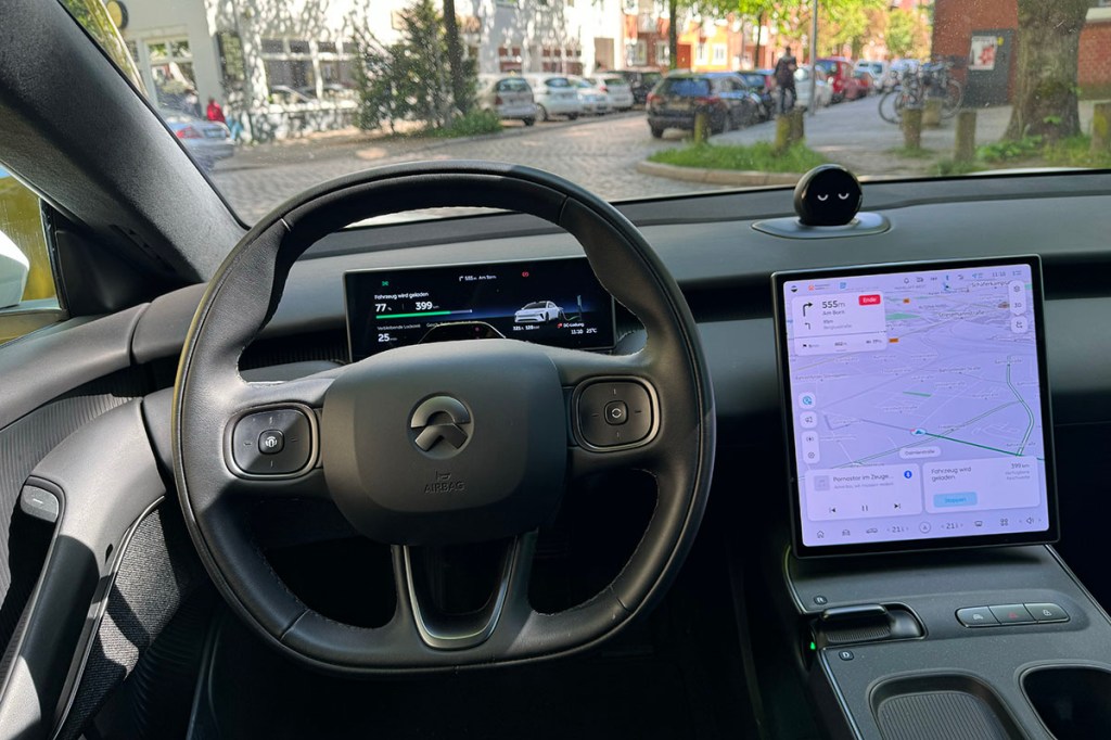 Blick durch die Windschutzscheibe aus dem Cockpit des E-Autos Nio ET5 Touring mit Lenkrad, Infortainment-Display.