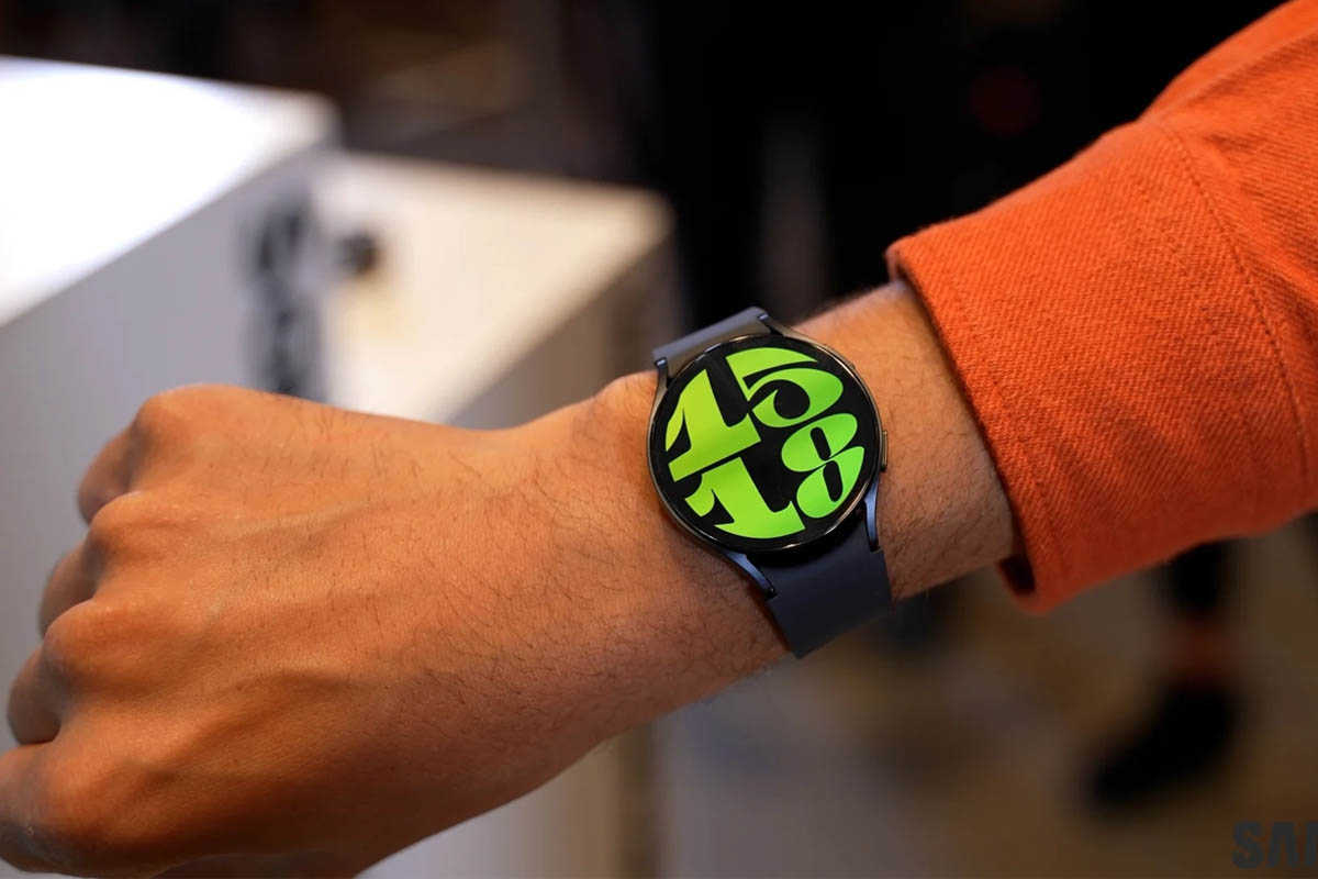 Eine Galaxy Watch 7 mit grünen Zahlen an einem Arm mit orangem Ärmel.