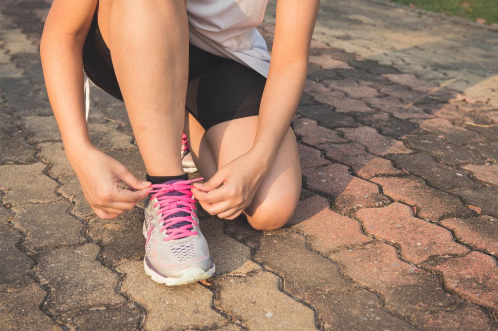 Eine Frau schnürt sich die Laufschuhe