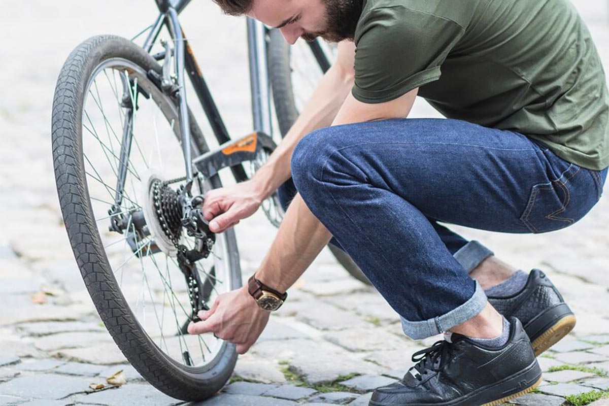 Person hockt neben einem Fahrrad mit den Händen an der Kette.