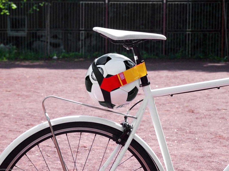 Anschnitt Fahrrad, an dem per Gurt ein Fußball befestigt ist