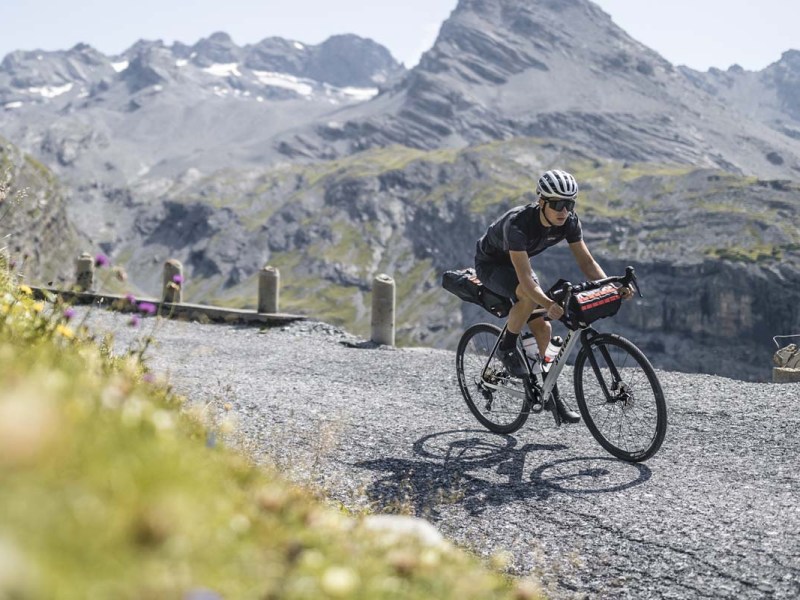 Person fährt mit einem Gravelbike durch eine Naturlandschaft in den BErgen