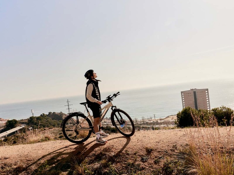 Person auf einem E-Bike, Natur und Meer im Hintergrund