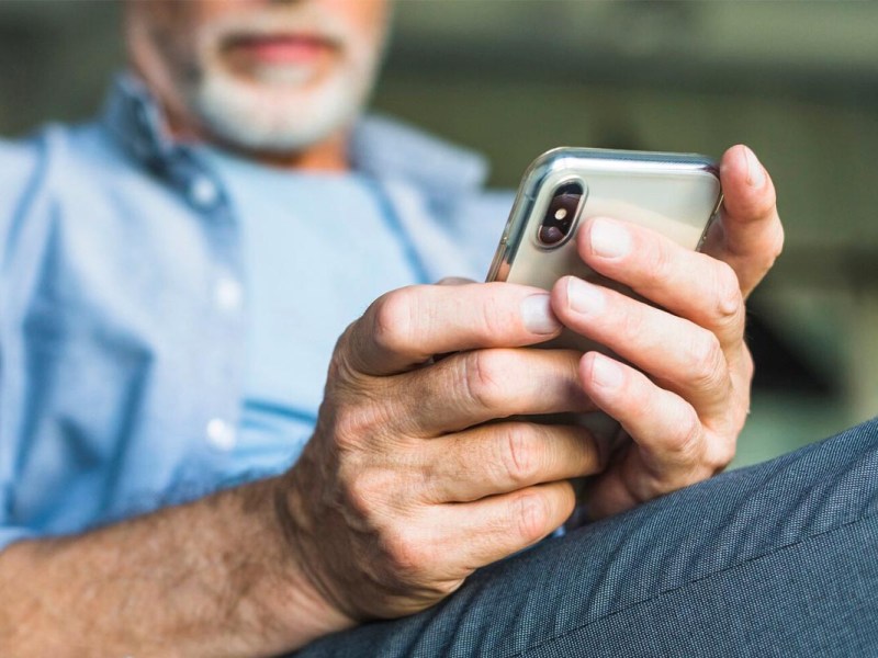 Älterer Mann mit einem Smartphone in der Hand.