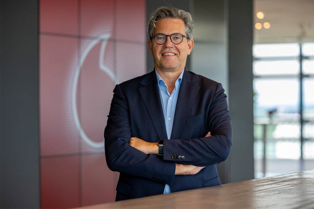 ARCHIV - 29.05.2024, Nordrhein-Westfalen, Düsseldorf: Marcel de Groot, der neue CEO von Vodafone Deutschland, steht in der Firmenzentrale vor einer Wand mit dem Vodafone-Logo.