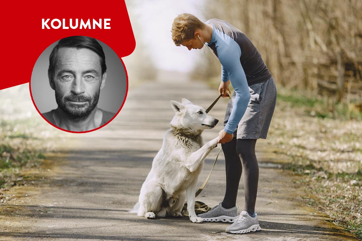 Läufer mit Hund auf einem Waldweg.