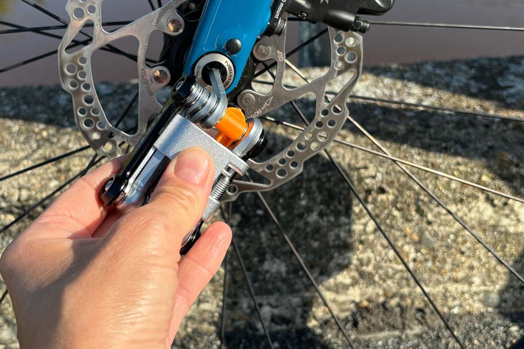 Nahaufnahme Hand, die ein Multitool hält und an einer Fahrradnabe schraubt