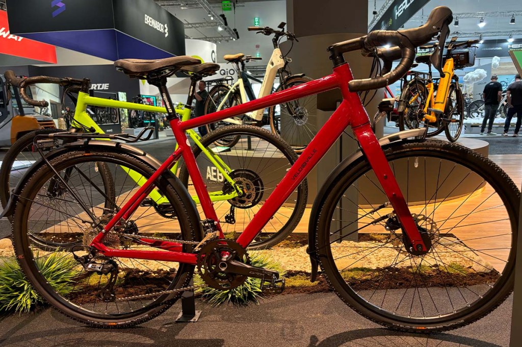 rotes Gravelbike von der SEite an einem Messestand