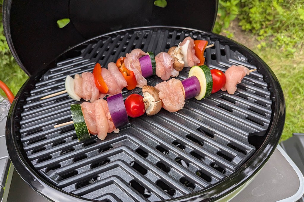 Zwei Spieße mit Fleisch und Gemüse auf einem Grillrost.