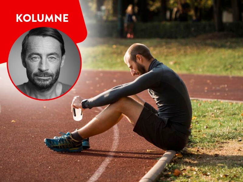 Person in Laufklamotten sitzt am Rand einer Strecke.