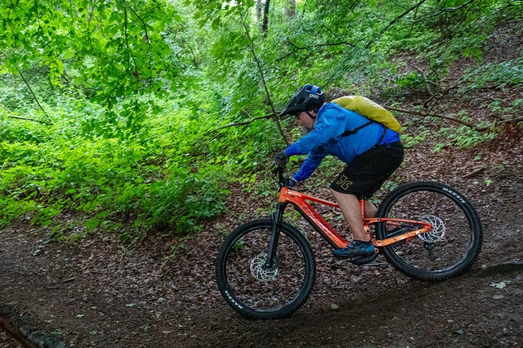 Fann fährt mit einem Mountainbike eine steile Passage im Wald herunter