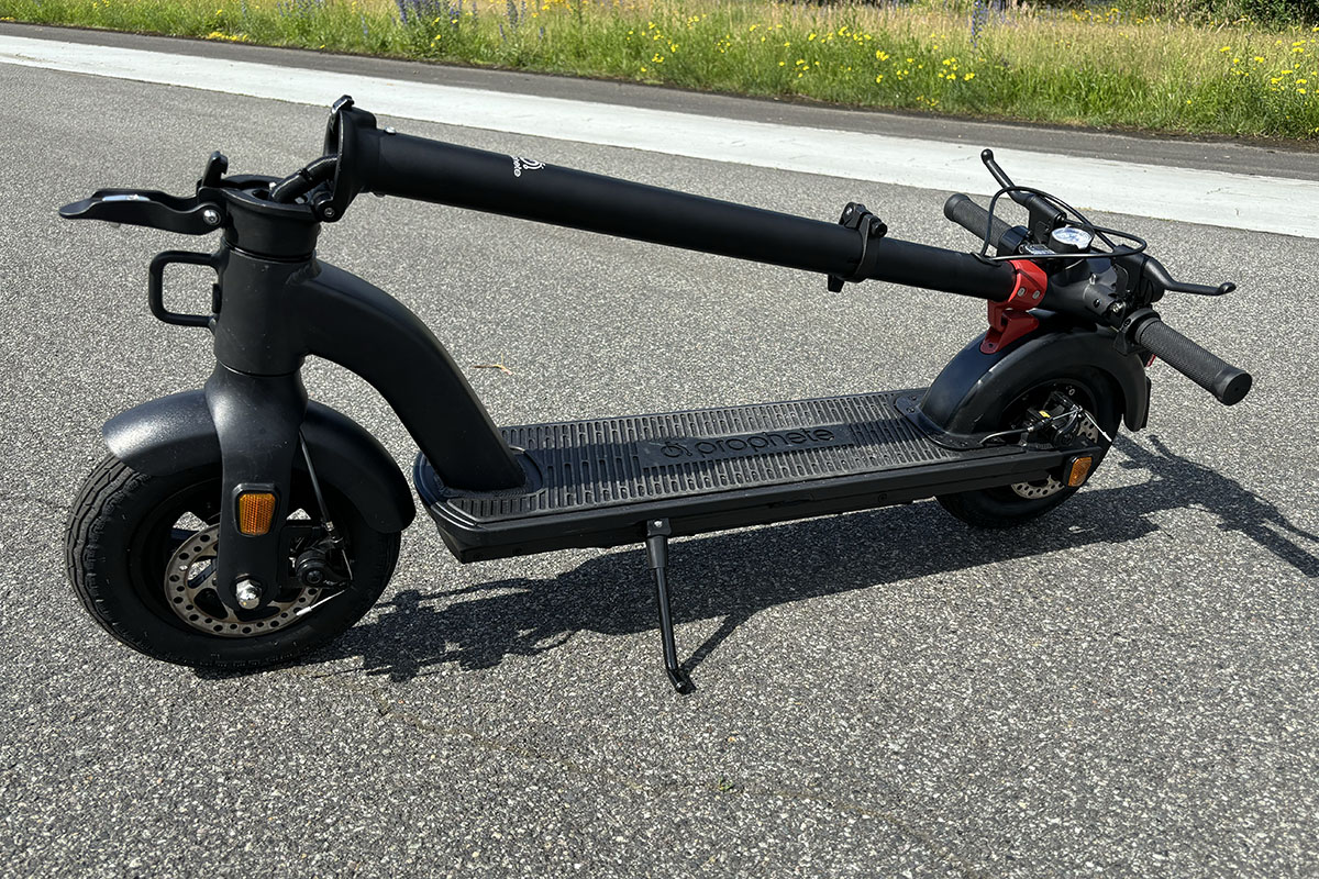 E-Scooter mit eingeklappten Lenker steht im Profil auf einer Straße.