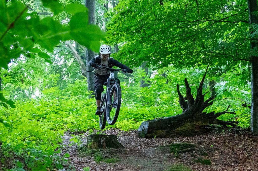 Mann springt mit seinem Mountainbike über ein Hindernis