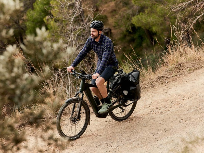 Radfahrer, fährt mit seinem E-Bike über einen Schotterweg in der Natur