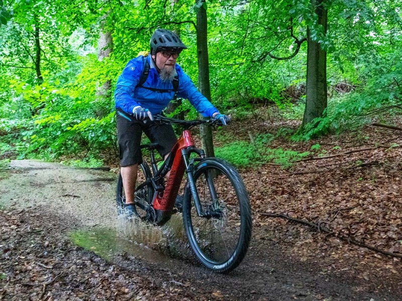 Mann fährt mit einem E-Moountainbike durch den Wald