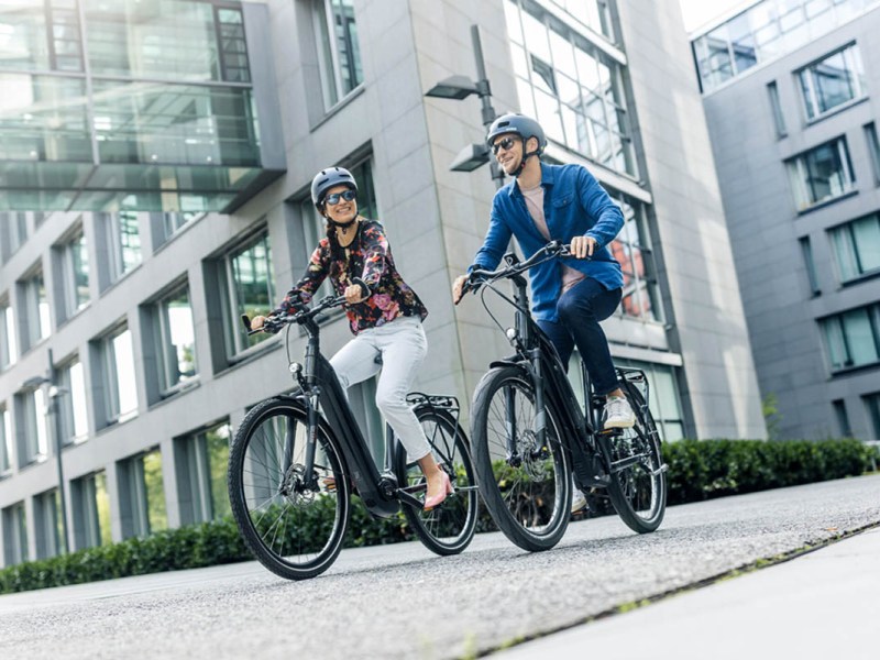 Zwei Menschen cruisen mit E-Bikes durch die Stadt.