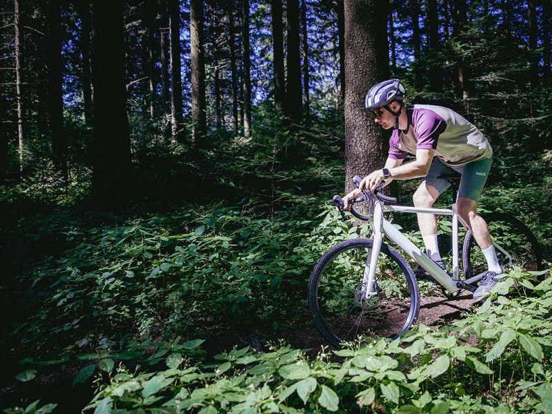 Person mit einem Gravel-E-Bike, die durch den Wald fährt