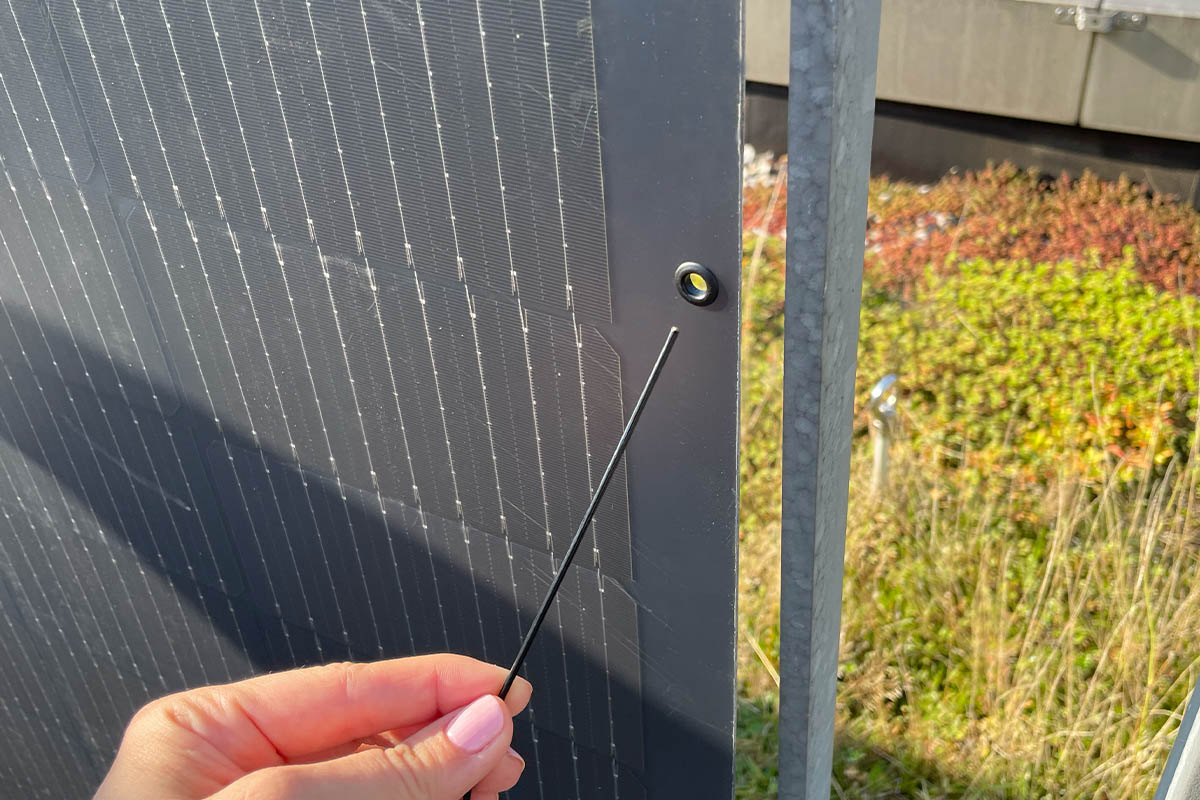 Eine Person fädelt ein Band in eine Öse des Jackery-Solarpanels.