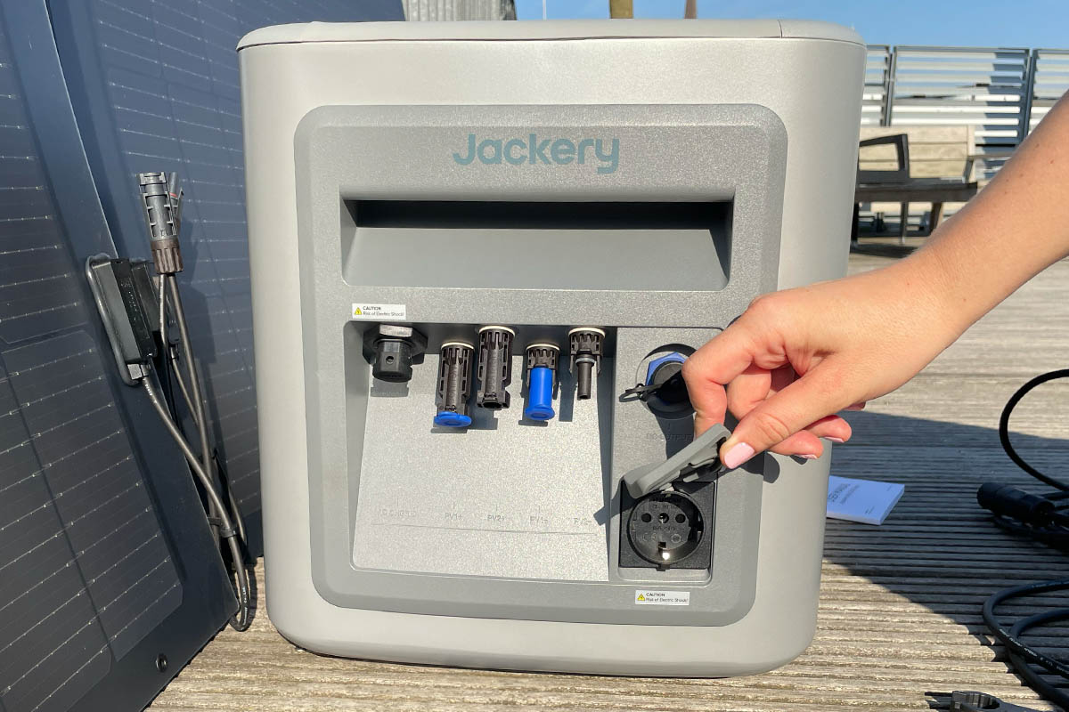 Eine Hand hält die Abdeckung der Steckdose am Navi 2000 offen.