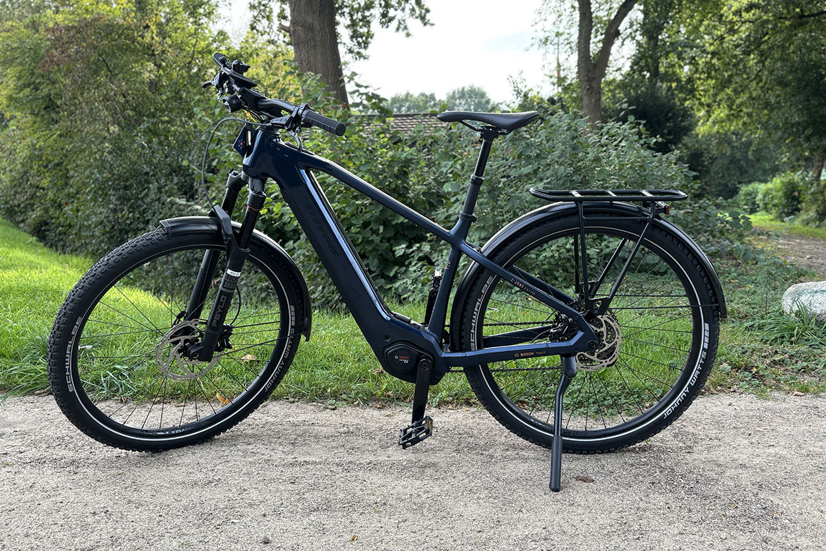 Vollausgestattetes Trekking-E-Bike Stevens E-Juke steht vor einer Rasnefläche.