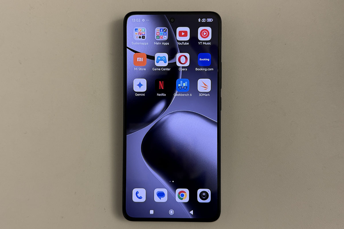 Smartphone Xiaomo 14T in frontaler Ansicht mit eingeschaltetem Display, das unterschiedliche App-Symbole anzeigt. Das Gerät liegt auf einer weißen Tischplatte.