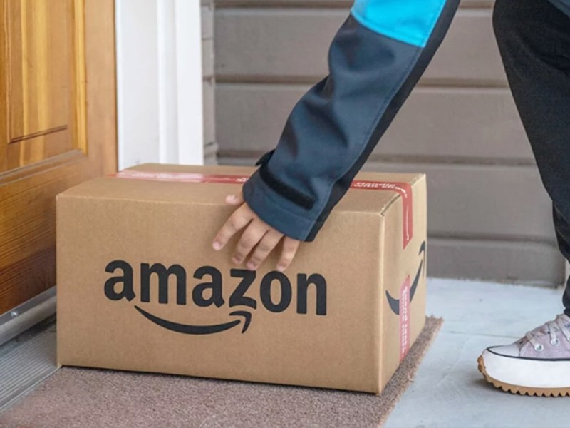 Eine Person legt ein Amazon-Paket auf eine Türmatte.