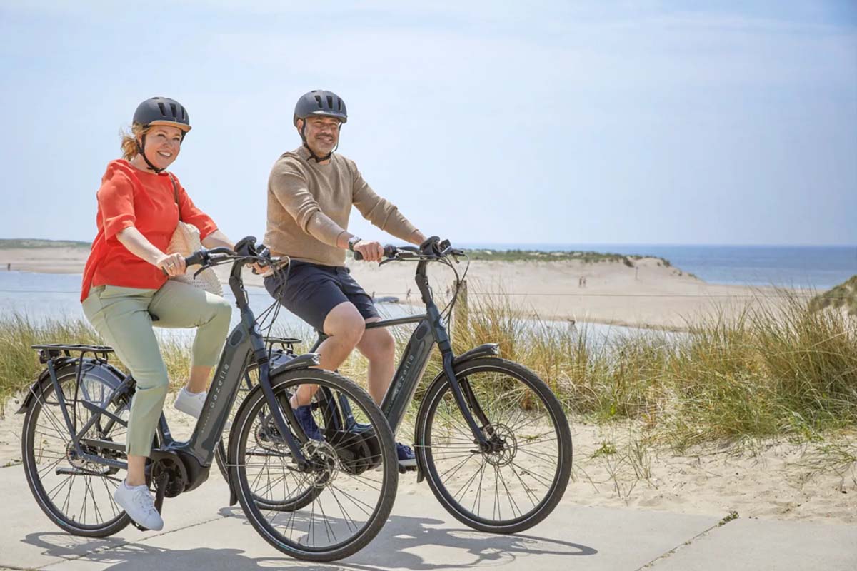 zwei Personen fahren mit dem E-Bike an einem Strand entlang