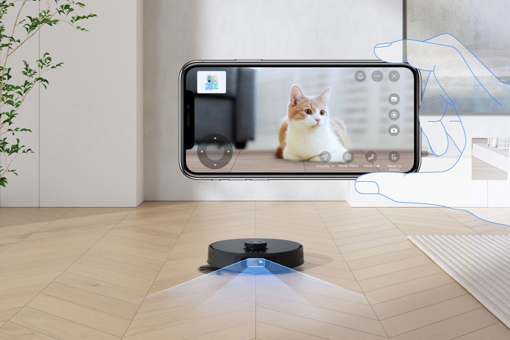 Der Deebot T30S Pro fährt in einem Wohnzimmer auf die Kamera zu. Blaue Linien zeigen schematisch die Navigation an. Eine durchsichtige Hand hält zudem ein Smartphone ins Bild, auf dem ein Video-Stream einer Katze zu sehen ist.