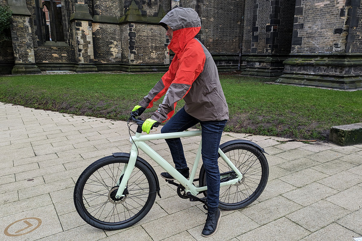 Mann mit Regenjacke bekleidet sitzt auf einem Fahrrad,