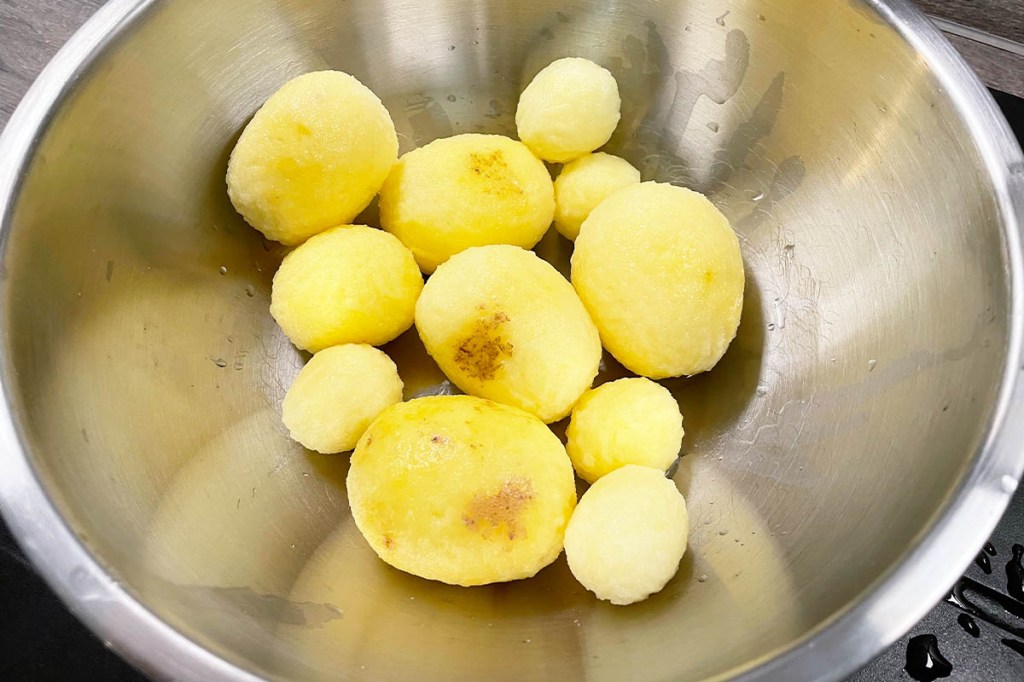 Geschälte Kartoffeln in einer Metallschüssel.