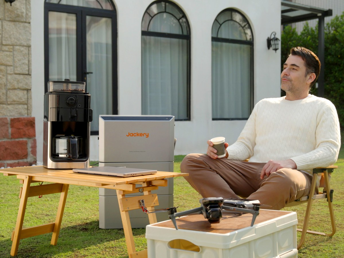 Mann sitzt im Garten vor der Jackery HomePower 2000 Ultra.