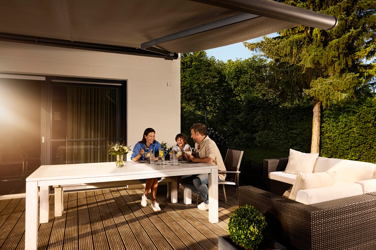 Eine Familie sitzt am Gartentisch.
