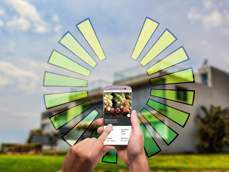Eine Hand mit Smartphone vor einem Haus